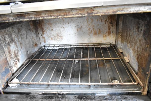 Garland SunFire stainless steel commercial gas oven interior, showing rust and wear. Part of a 6-burner range with shelf.