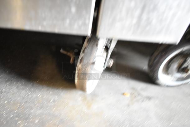 Blurry close-up of commercial caster wheel under a Garland stainless steel gas-powered range, indicating mobility feature.