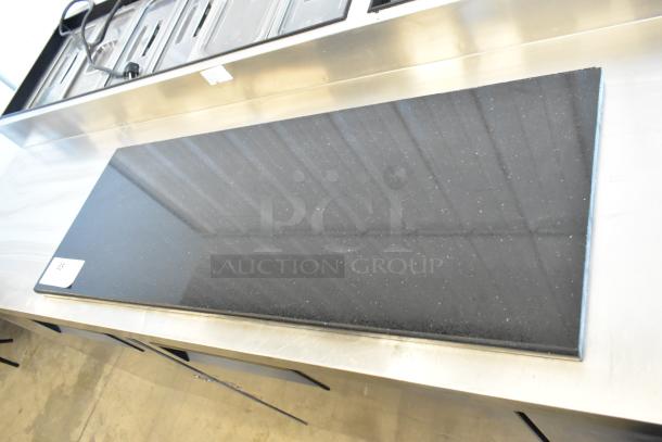 Black granite countertop in excellent condition on stainless steel base; glossy finish with subtle speckled pattern.