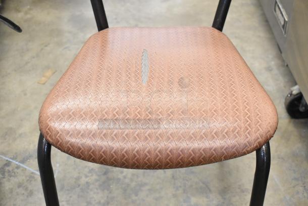 Dining height chair with textured tan seat cushion, visible wear on cushion. Black metal legs, sturdy construction.
