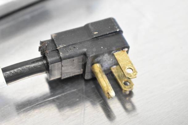 Close-up of a power plug from a Beverage Air SPE48C prep table. Black casing with visible wear and brass prongs.