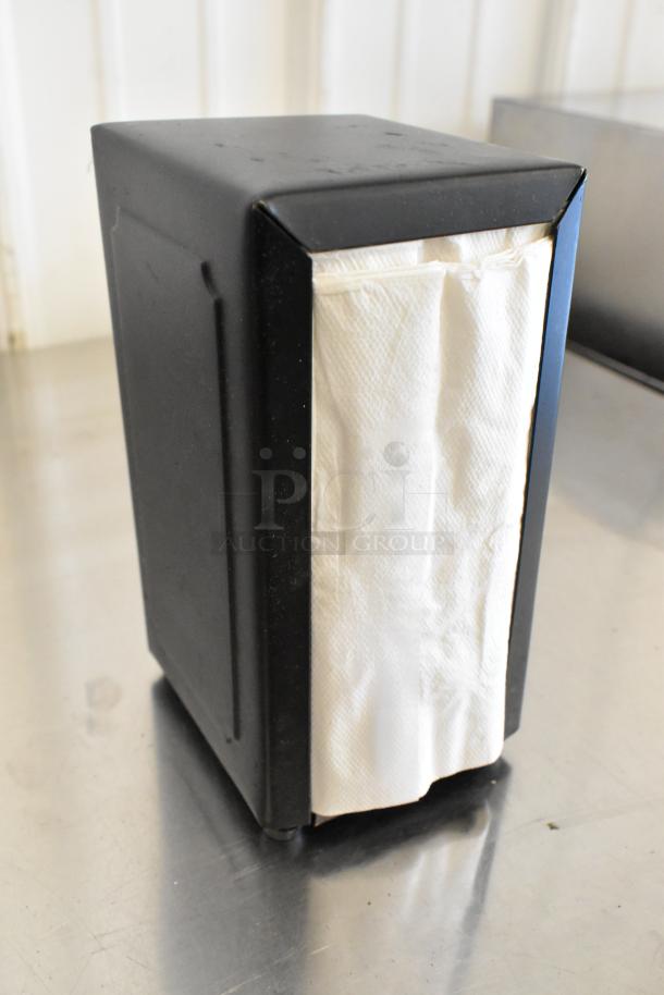 Black metal napkin dispenser, sleek design, holds folded napkins, durable condition. Auction item: 10 dispensers total.