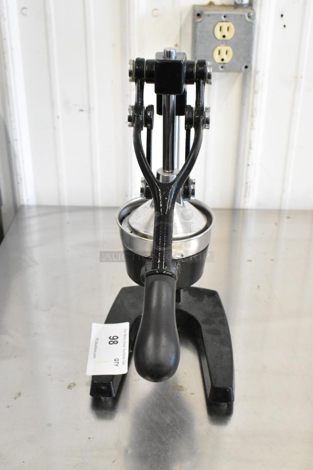 Metal manual citrus juicer with sturdy black handle and stainless steel components. Item tag indicates auction lot 98.