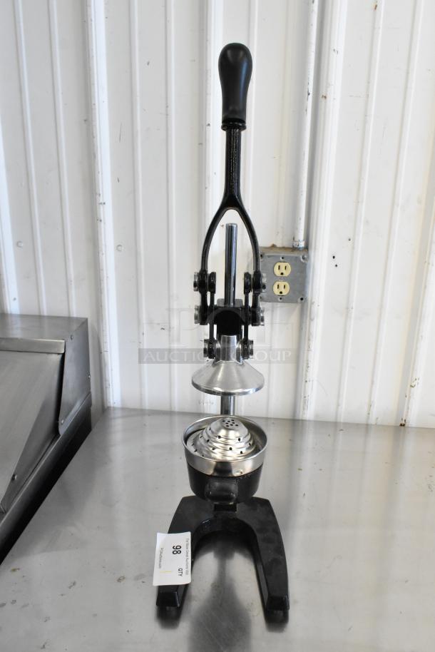 Metal manual citrus juicer with sturdy black handle, stainless steel pressing cone and base. Auction tag indicates lot 98.