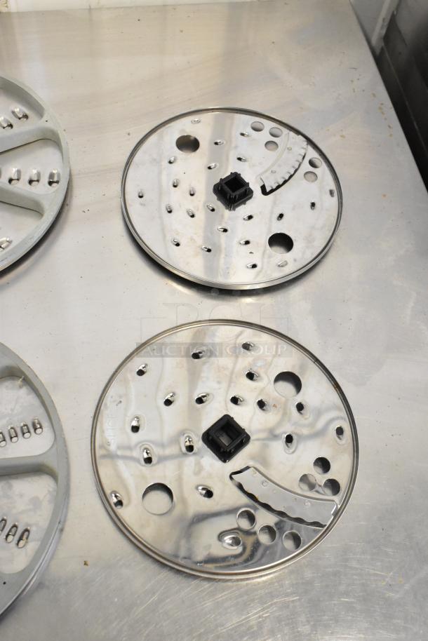 10 food processor blades on metal surface, featuring diverse slicing patterns and black central hubs, in excellent condition.