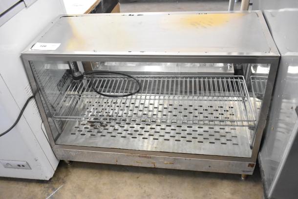 Metal countertop display case merchandiser with adjustable shelves, visible power cord, and signs of wear on the exterior.