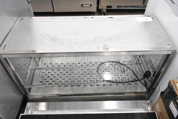 Metal countertop display case merchandiser, stainless steel with two wire shelves, glass front. Used condition, visible markings.