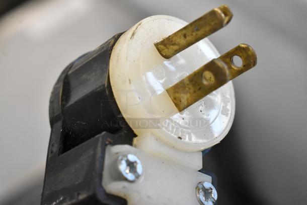 Close-up of a black and white electrical plug with metal prongs. No display case visible.