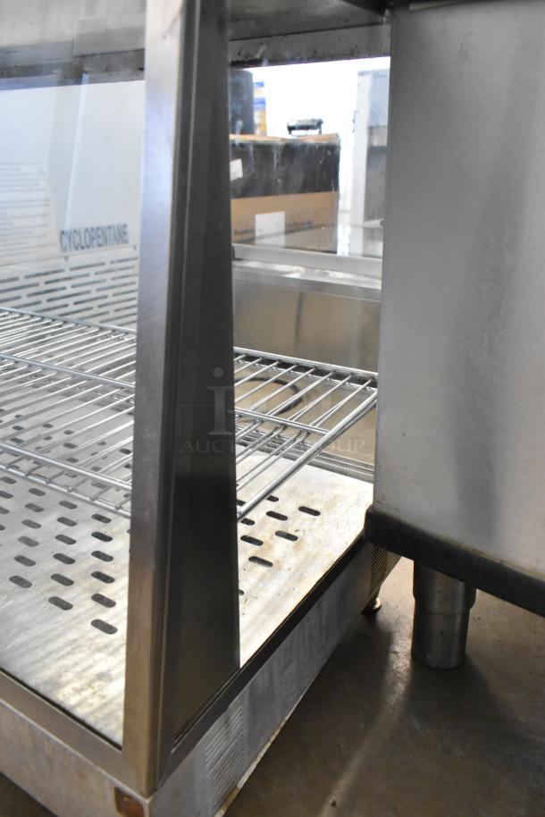 Metal countertop display case merchandiser with wire shelving, stainless steel frame, and ventilation holes, in good condition.
