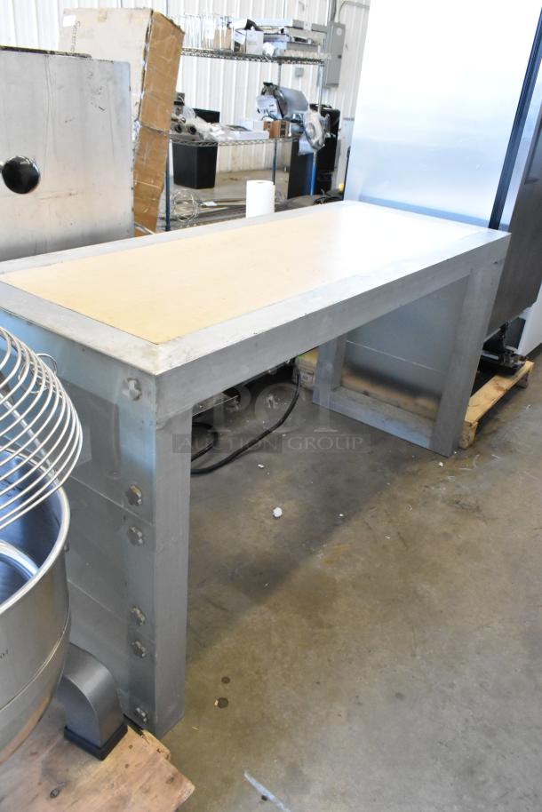 Stainless steel table with a wooden top, industrial style, sturdy construction, in used condition. Auction includes two tables.