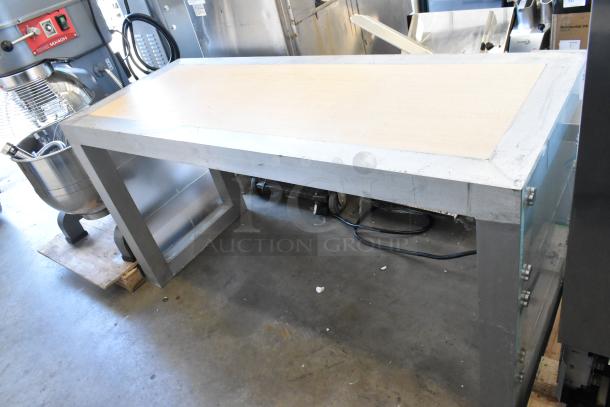 Stainless steel work table with wood top, industrial setting, sturdy construction, good condition, auction item.