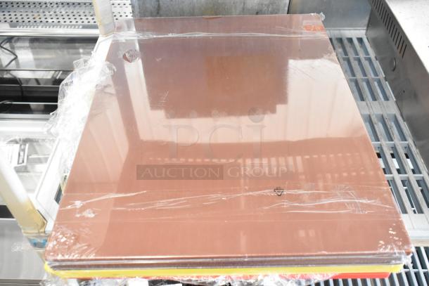 Seven brand new scratch and dent cutting boards, including Choice 24"x18" yellow polyethylene, brown, and red boards, sealed in plastic.