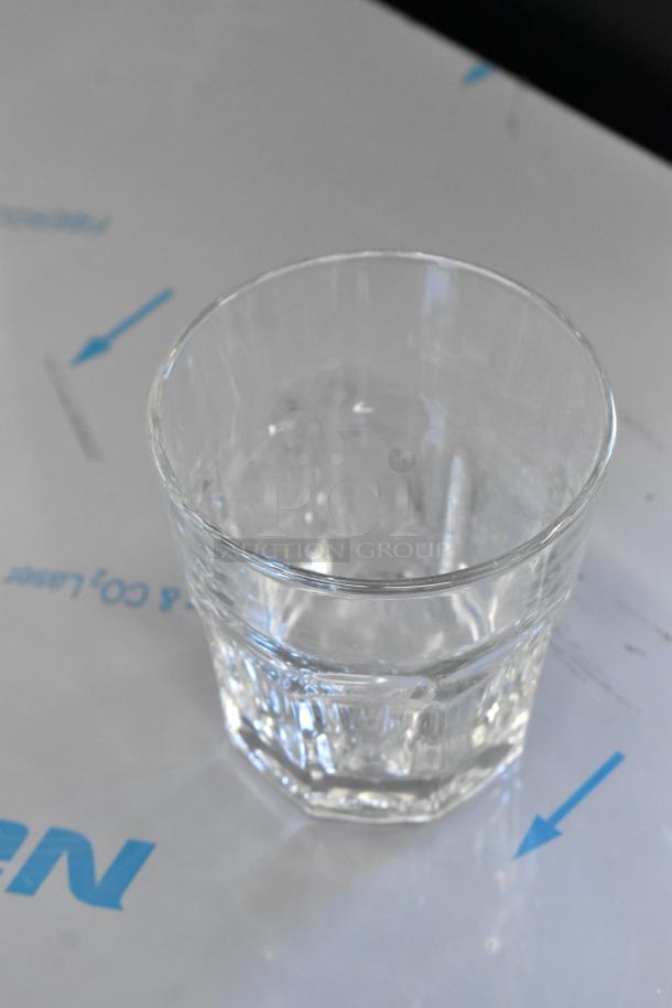 Clear glass tumbler with faceted design on protective surface, showcasing clarity and condition.