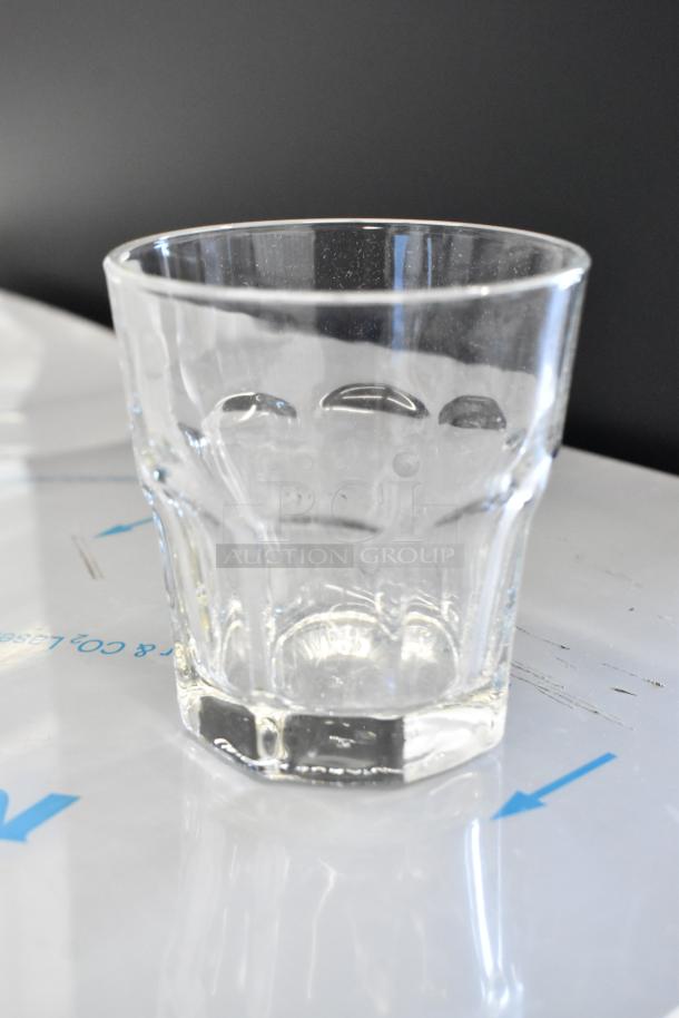 Clear glass tumbler with a faceted design on a white surface. Excellent condition, suitable for various beverages.