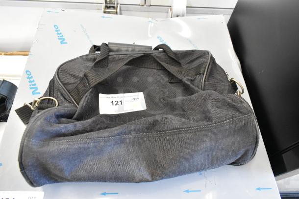 Two black bags including Porta Brace with visible wear, ID tag marked "121," leather handle, and metal clasps.