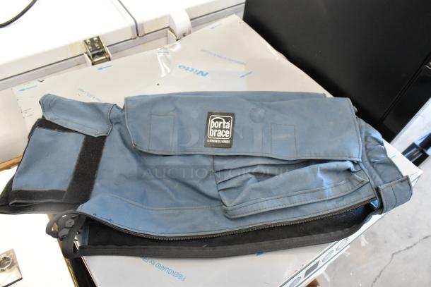 Two blue utility bags, including a Porta Brace with visible logo, zipper, and Velcro closures. Moderate wear.