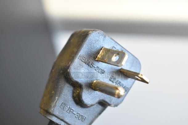 Close-up of a plug labeled "NEMA 5-20P E245649 ECP-3006," indicating it's for electrical equipment.