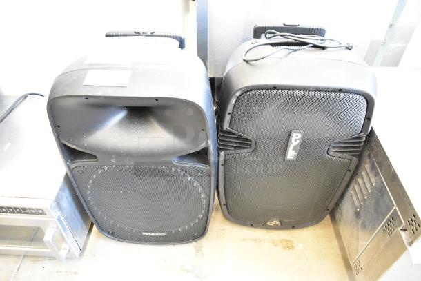 Two Pyle speakers, models PPHP1569UT and PPHP1599WU, in used condition. Black casing with front grills visible.