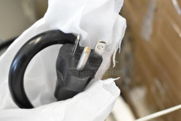 Power plug of a KoolMore KM-CWO24-AFSS speed oven, 120 volts, shown wrapped in protective packaging.