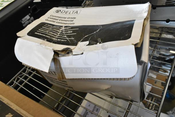 Brand new Delta faucet in original packaging with visible scratches and dents on the box. Commercial grade, 5-year warranty label.