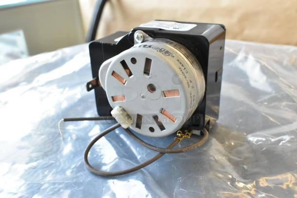 Alt text: Electric component with a metal circular fan housed in a black casing, featuring exposed copper elements and attached wires.