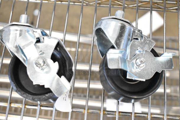 Lot of 2 brand new commercial casters with minor scratches. Metal housing, black wheels, intact threads, on wire rack.