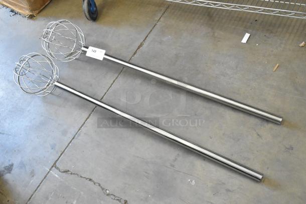 Two brand new metal mixing whisks with long handles, visible scratch and dent, item tag reads "149."
