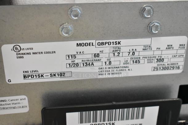 BRAND NEW SCRATCH AND DENT! Oasis QBPD1SK floor water cooler base, 115 volts, 1 phase. Label shows model details and specs.