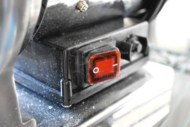 Close-up of a Backyard Pro 554BSG12 meat grinder switch. Dusty surface with visible red on/off button on black casing.