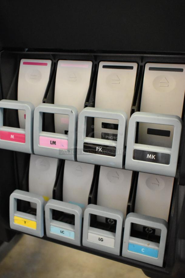 HP DesignJet Z6100 printer ink cartridge slots, labeled M, LM, PK, MK, Y, LC, LG, C. 115 volts, 1 phase operation.