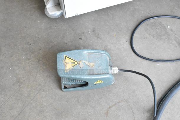 GBC GBC3064WF printer foot pedal with cable on concrete floor. Worn caution label visible.