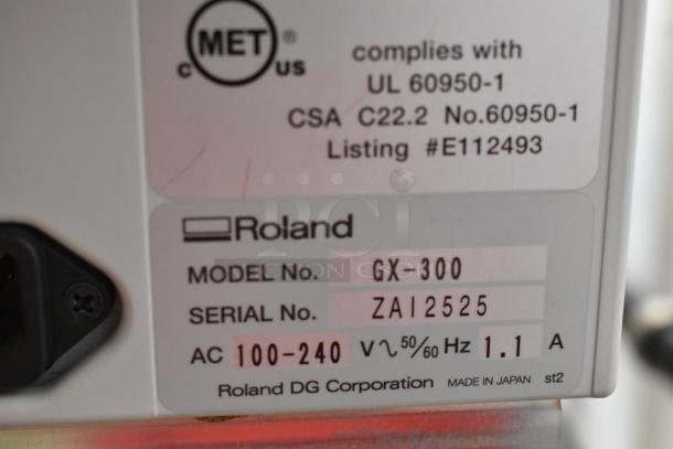 Roland Camm-1 Pro GX-300 label showing model GX-300, serial ZAI2525, AC 100-240V, 50/60Hz, 1.1A, marking compliance info.