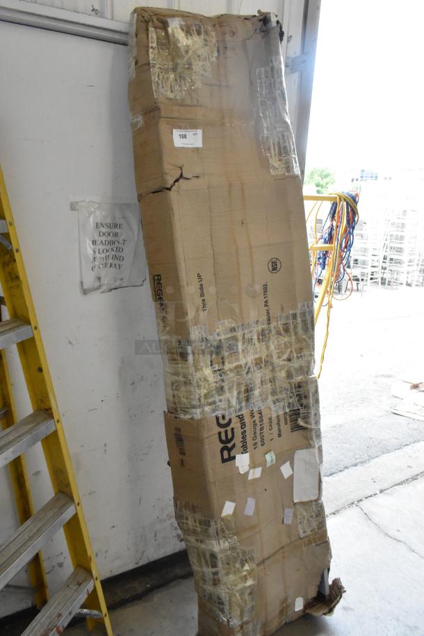 Damaged packaging of a new Regency 600TB1884G stainless steel commercial work table with backsplash and undershelf.