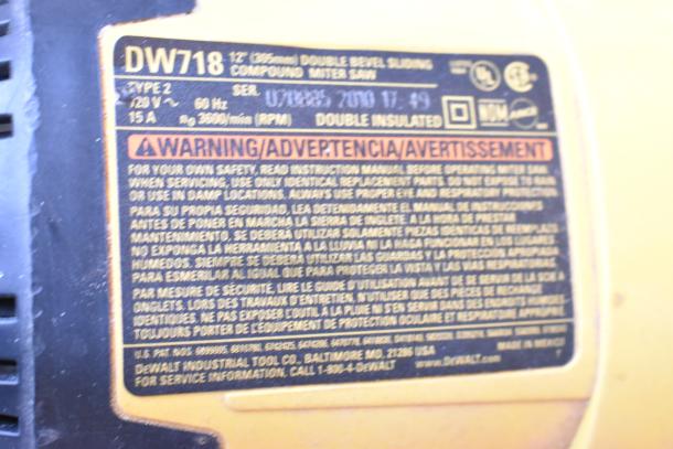 "DeWalt DW718 miter saw label showing model details, voltage, amperage, safety warnings, and manufacturer contact info."