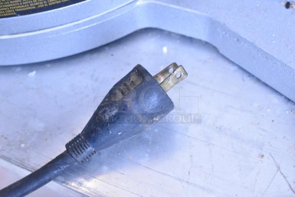 DeWalt DW718 miter saw power cord on metal surface, showing a worn, dusty plug with visible prongs.