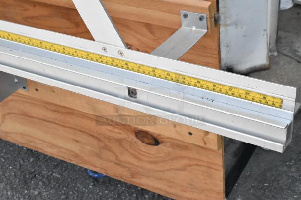 Fletcher 3100 63" Multi-Material Cutter with metal handle, measurement markings, on a wooden surface, commercial casters visible.