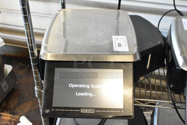 Hobart digital scale with touchscreen displaying "Operating System Loading," metal platform, auction tag labeled "101."