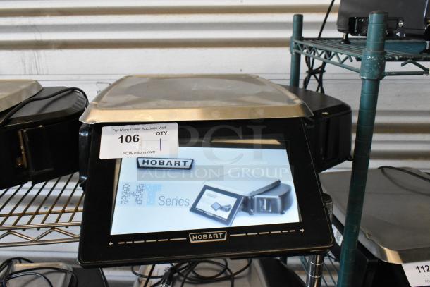 Hobart NT Series touchscreen scale on metal shelf, model displayed. Auction tag 106 visible, indicating quantity of one.