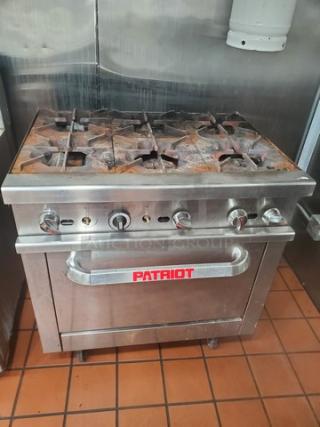 Patriot Natural Gas 6 Burner Range w/ Standard Oven. No Backsplash. Missing two knobs. On Casters