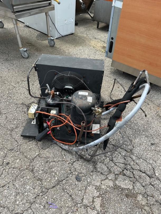 Commercial refrigeration compressor unit with wiring and coils, in used condition. Labels present, indicating specs and model.
