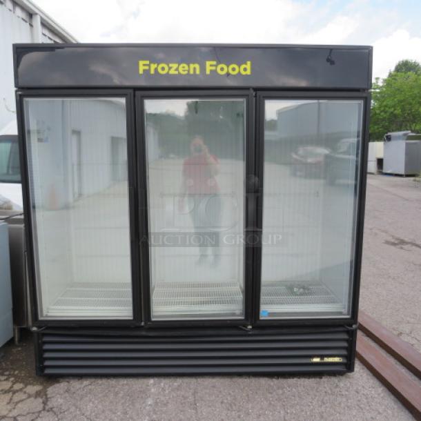 Black three-door commercial freezer labeled "Frozen Food," glass fronts, adjustable shelves, used condition.