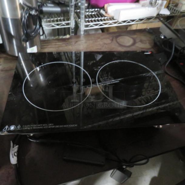 Black double-burner induction cooktop, glass surface, electric, good condition, caution label warns of hot surface.