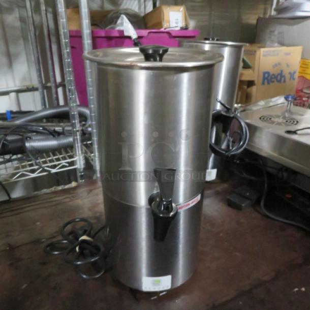 Stainless steel commercial coffee urn, featuring a black spigot and power cord, in good condition.