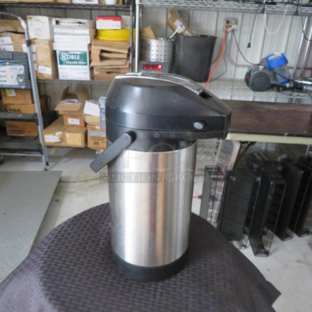 Stainless steel airpot with black plastic top, lever dispenser, and handle. Used condition, minor scuffs, no visible brand markings.