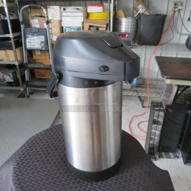 Stainless steel airpot with black lid and handle, used condition, ideal for serving hot beverages.