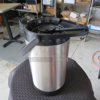 Stainless steel airpot coffee dispenser with black handle, in used condition. Ideal for catering or large gatherings.