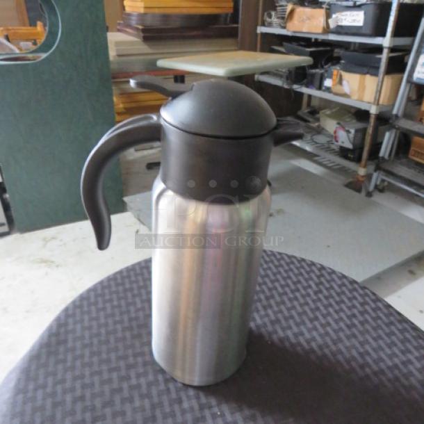 Stainless steel thermal carafe with black lid and handle, used condition. Matte finish, suitable for hot or cold beverages.
