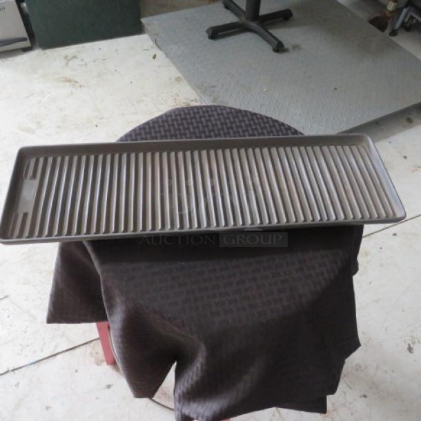 Rectangular metal grilling tray with raised ridges, in good condition, on a dark cloth-covered table.