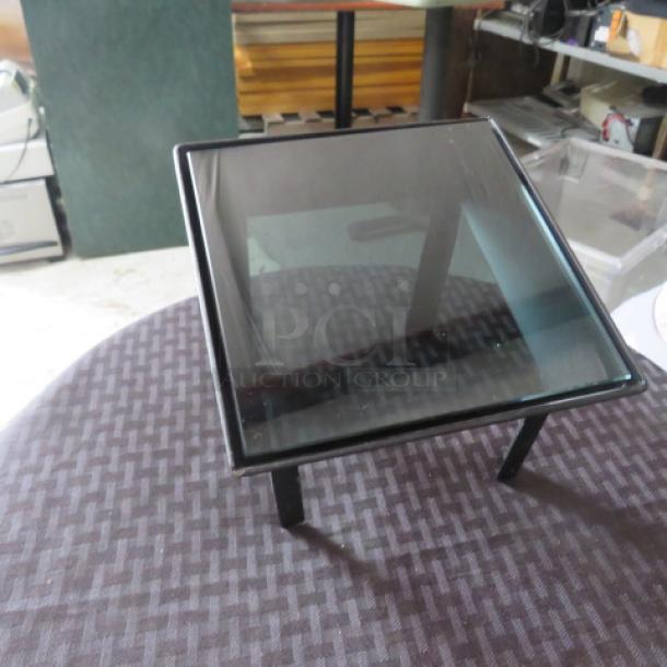Square glass-top side table with black metal frame, excellent condition. Features minimalist design, ideal for modern interiors.