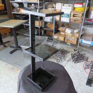 Black metal display stand with three tiered glass shelves, showing minimal wear. Sturdy design, suitable for retail.